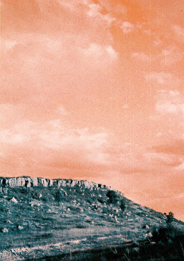 A blurry blue hill under a grainy orange sky, taken in portrait