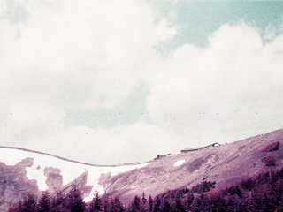 A distant building on a purple hill under a green, partly-cloudy sky