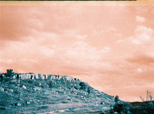 A blurry blue hill under a grainy orange sky, taken in landscape