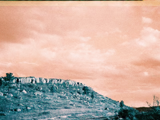 A blurry blue hill under a grainy orange sky, taken in landscape